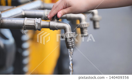 Child hand turning water faucet, saving natural resource and promoting sustainability Child hand turning water faucet, saving natural resource and promoting sustainability 140409356