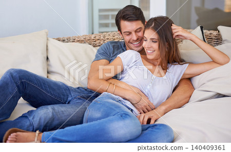 Happy couple, hug and relax on sofa with love for bonding, care or embrace in comfort at home. Man and woman lying on living room couch with smile for support, romance or holiday weekend at house 140409361