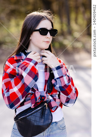 Young stylish woman adjusting headphones while listening to music outdoors Young stylish woman adjusting headphones while listening to music outdoors 140409482