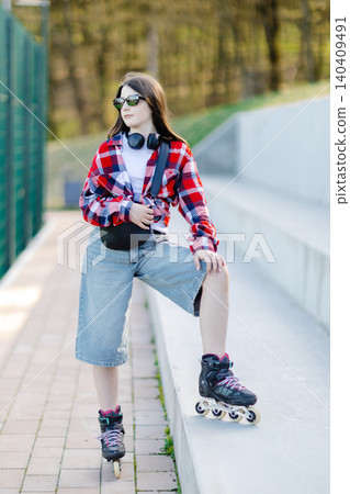 Stylish teenager waving while posing with inline skates in an urban setting 140409491