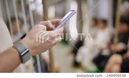 Hands holding smartphone, connecting and communicating on subway train Hands holding smartphone, connecting and communicating on subway train 140409530