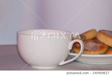 Side view of white ceramic cup with blurred sweet pancakes on a plate Side view of white ceramic cup with blurred sweet pancakes on a plate 140409617