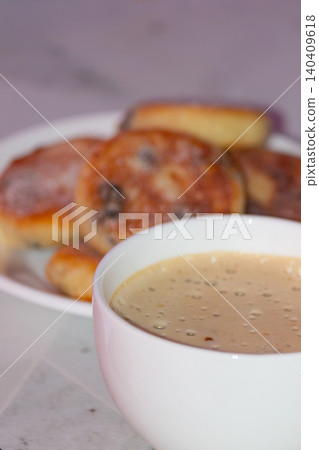 Vertical close up of coffee cup with blurred sweet pancakes on a plate Vertical close up of coffee cup with blurred sweet pancakes on a plate 140409618