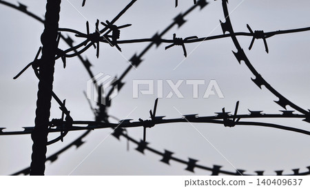 Barbed wire fence creating a strong barrier against intruders Barbed wire fence creating a strong barrier against intruders 140409637