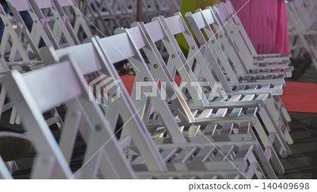 Empty white folding chairs creating audience seating for a fashion event or show Empty white folding chairs creating audience seating for a fashion event or show 140409698