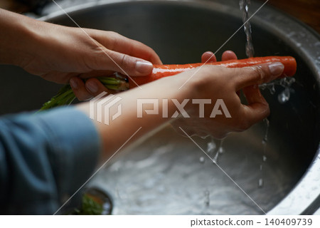 Hands, carrots and washing vegetables or healthy food in sink, preparing meal and kitchen while ready to cook. Person, rinsing fresh produce in basin at home for diet or organic recipe for wellness 140409739