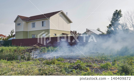 Burning grass and dry brush near modern house in Moscow causing air pollution Burning grass and dry brush near modern house in Moscow causing air pollution 140409872