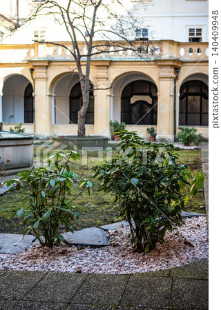 Peaceful courtyard with shrubs and arched building Peaceful courtyard with shrubs and arched building 140409948