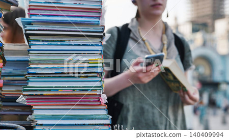 Stacks of books at a Moscow street market with a girl using smartphone Stacks of books at a Moscow street market with a girl using smartphone 140409994