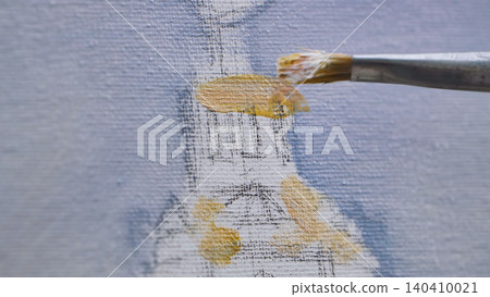 Artist painting with brush on canvas, adding yellow ochre color to artwork Artist painting with brush on canvas, adding yellow ochre color to artwork 140410021