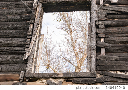 Burnt house window frame showing destruction and the bare trees of nature changing Burnt house window frame showing destruction and the bare trees of nature changing 140410040