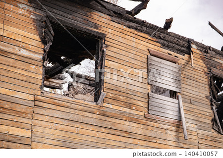 Burnt building exterior with charred wood planks and broken windows from a house fire Burnt building exterior with charred wood planks and broken windows from a house fire 140410057
