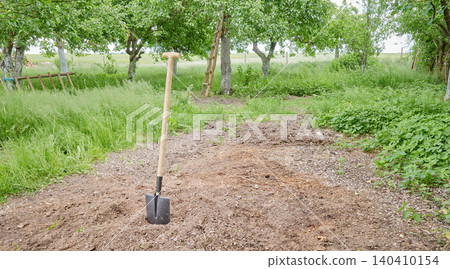 A shovel stuck in the ground covered with sawdust in the garden. A shovel stuck in the ground covered with sawdust in the garden. 140410154