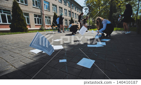Students throwing papers in the air after passing exams near school building on a sunny summer day 140410187
