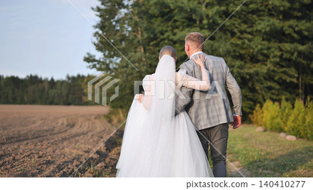 Newlywed couple strolling through nature, enjoying the peaceful scenery after their wedding ceremony Newlywed couple strolling through nature, enjoying the peaceful scenery after their wedding ceremony 140410277