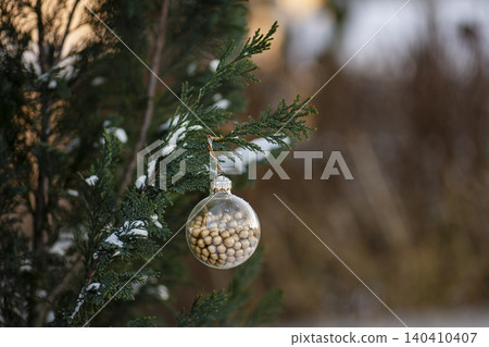 Outdoor natural light illuminates glass ball from multiple angles revealing texture and color of golden bead filling within sphere. 140410407