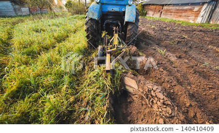 Blue tractor plowing a field, preparing soil for cultivation, illustrating agricultural practices and land cultivation Blue tractor plowing a field, preparing soil for cultivation, illustrating agricultural practices and land cultivation 140410409