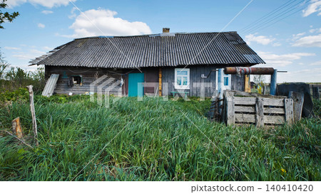 Run-down rustic village house with overgrown grass and old well in countryside Run-down rustic village house with overgrown grass and old well in countryside 140410420