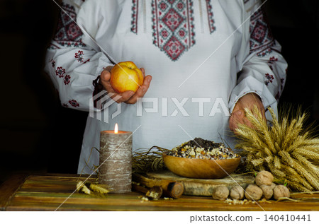 Woman in embroidered ukrainian dress serves christmas kutia on festive table. Woman in embroidered ukrainian dress serves christmas kutia on festive table. 140410441
