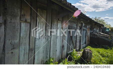 Weathered rustic wooden barn wall at countryside homestead with green grass and blue sky Weathered rustic wooden barn wall at countryside homestead with green grass and blue sky 140410480