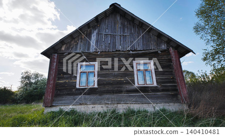 Old weathered wooden house in a rural field under a cloudy sky Old weathered wooden house in a rural field under a cloudy sky 140410481