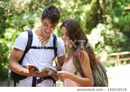 Couple, map and reading for hiking in woods with smile for thinking, holiday and ideas on path. Man, woman and bag for trekking, direction and search in rainforest with book for location in Colombia Couple, map and reading for hiking in woods with smile for thinking, holiday and ideas on path. Man, woman and bag for trekking, direction and search in rainforest with book for location in Colombia 140410526