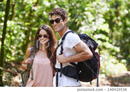 Happy couple, backpack and hiking with sunglasses in nature for adventure or outdoor journey together. Young man, woman or hiker with smile, bag and bonding for trekking or walk in forest or woods Happy couple, backpack and hiking with sunglasses in nature for adventure or outdoor journey together. Young man, woman or hiker with smile, bag and bonding for trekking or walk in forest or woods 140410536