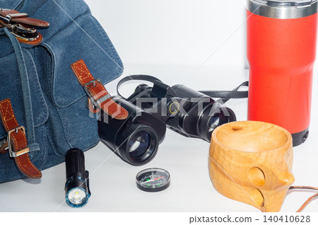 Backpack, compass, binoculars and flashlight, camping mug and thermos-a hiking kit. Backpack, compass, binoculars and flashlight, camping mug and thermos-a hiking kit. 140410628