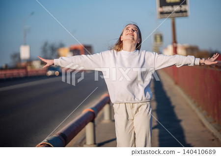 Young woman feeling freedom and joy on a city bridge during a sunny day Young woman feeling freedom and joy on a city bridge during a sunny day 140410689