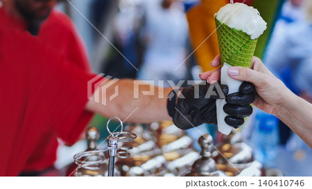 Street vendor holding pistachio ice cream cone at a local market Street vendor holding pistachio ice cream cone at a local market 140410746