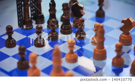 Wooden chess pieces standing on blue chessboard during match Wooden chess pieces standing on blue chessboard during match 140410770