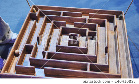 Wooden maze game challenging players to guide a ball through a complex labyrinth 140410853