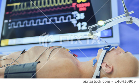 Patient receiving life support in intensive care unit with ventilator and medical monitor 140410909