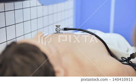 Patient lying on a medical bed receiving a chest examination with a stethoscope Patient lying on a medical bed receiving a chest examination with a stethoscope 140410913