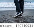 A man walks towards the water's edge on the beach. 140410931