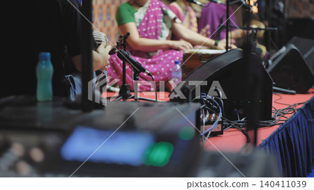 Musicians performing Indian traditional music with harmonium and sound equipment 140411039