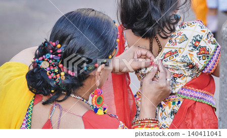 Preparing for Ganesha Chaturthi, Indian women dressing in colorful traditional clothing Preparing for Ganesha Chaturthi, Indian women dressing in colorful traditional clothing 140411041