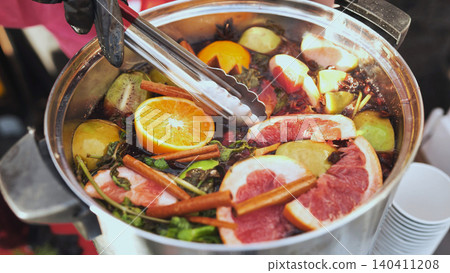 Fruit tea or mulled wine preparing in a pot with oranges, grapefruits, and cinnamon Fruit tea or mulled wine preparing in a pot with oranges, grapefruits, and cinnamon 140411208