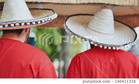 Two people wearing traditional Mexican sombreros and red shirts celebrating Cinco de Mayo Two people wearing traditional Mexican sombreros and red shirts celebrating Cinco de Mayo 140411338
