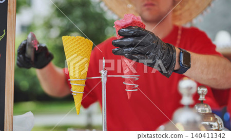 Street vendor preparing colorful ice cream cones for customers outdoors Street vendor preparing colorful ice cream cones for customers outdoors 140411342