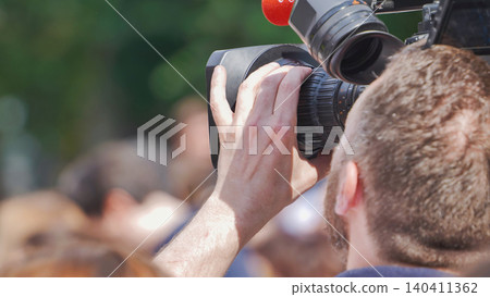 Cameraman filming crowd with professional video camera for live broadcast news Cameraman filming crowd with professional video camera for live broadcast news 140411362