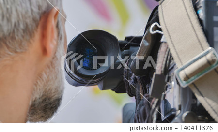 Cameraman filming with professional video camera, capturing important news events Cameraman filming with professional video camera, capturing important news events 140411376