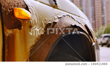 Rusty fender with peeling paint on damaged car parked on city street Rusty fender with peeling paint on damaged car parked on city street 140411469