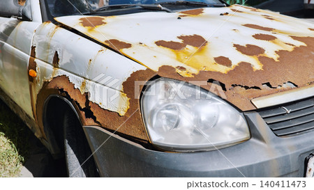 Rusty old white car parked on the street is decaying Rusty old white car parked on the street is decaying 140411473