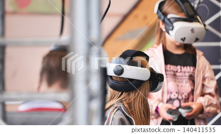 Girls experiencing virtual reality entertainment with VR headsets 140411535