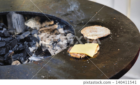 Preparing cheeseburger grilling on an outdoor barbecue 140411541