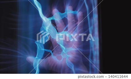 Hands interacting with a glass tube generating electricity and light energy Hands interacting with a glass tube generating electricity and light energy 140411644