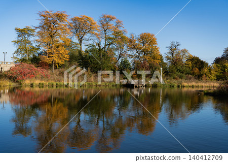 Park pond. Park in autumn with colorful fall trees. Autumn nature. Fall nature landscape. Lake in park with autumn tree and yellow fall seasonal leaves. Autumnal nature landscape 140412709