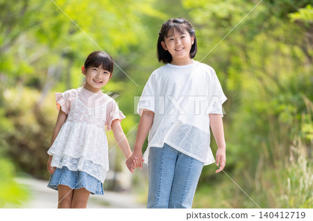 Two smiling girls walking hand in hand. Two smiling girls walking hand in hand. 140412719