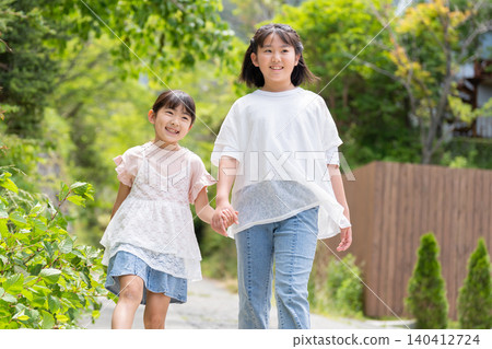 Two smiling girls walking hand in hand. Two smiling girls walking hand in hand. 140412724